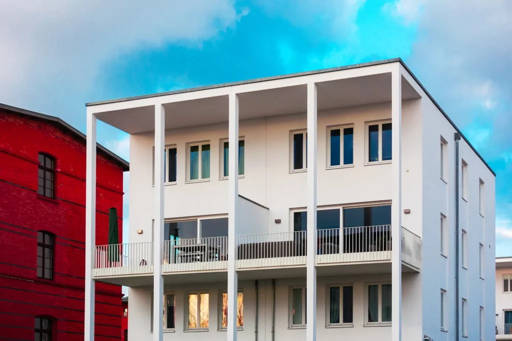 Bâtiment blanc moderne à côté d'une maison en briques Bâtiment blanc moderne à côté d'une maison en briques